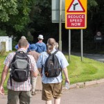 Walkers approaching a reduce speed now sign